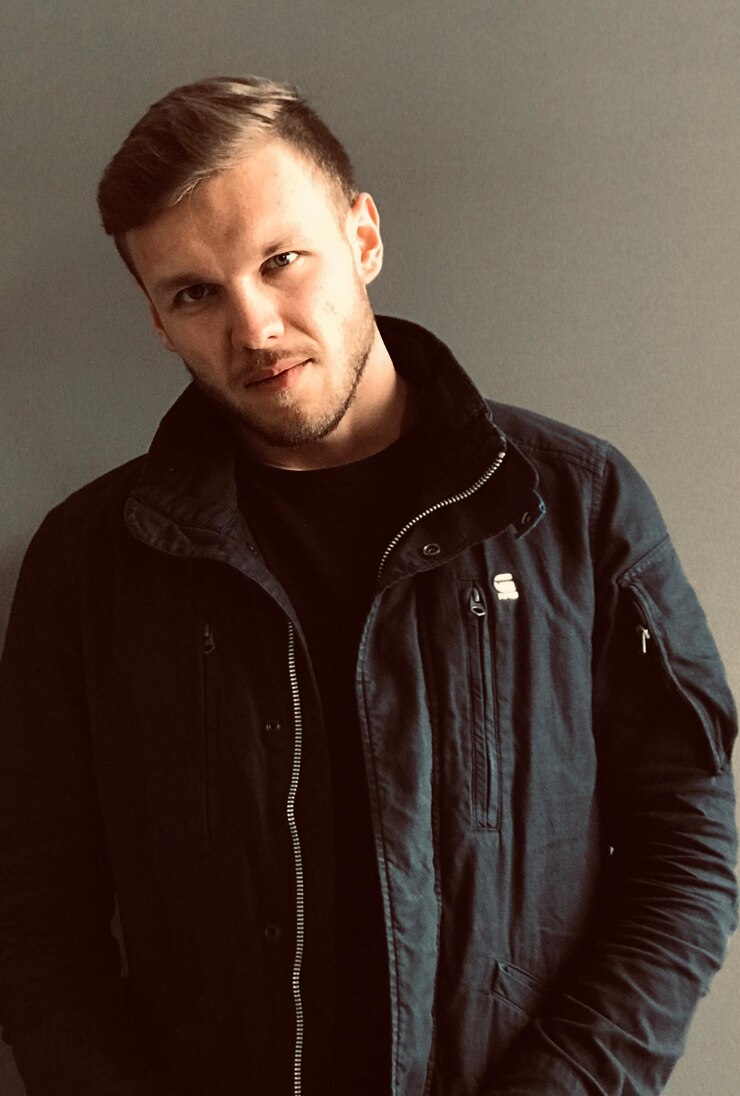 Foto portret van een jonge man die tegen een grijze achtergrond staat