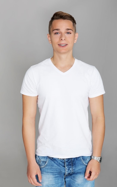 Portret van een jonge man die tegen een grijze achtergrond staat