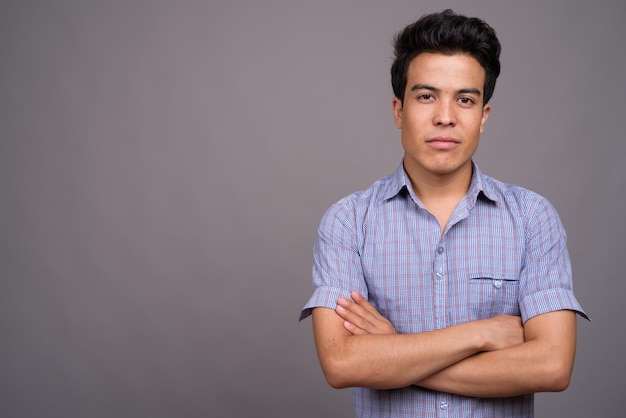 Portret van een jonge man die tegen een grijze achtergrond staat