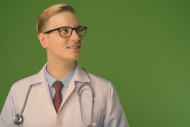 Foto portret van een jonge man die tegen een grijze achtergrond wegkijkt