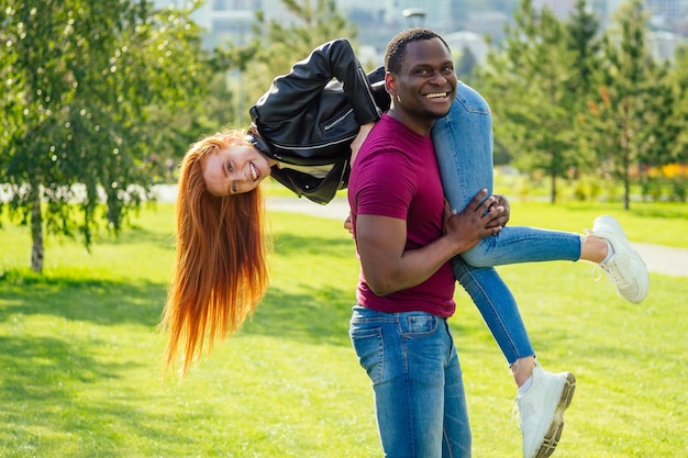 Portret van een jonge man die zijn vriendin knuffelt die samen op een lente-zomerpark staat op een zonnige dag.