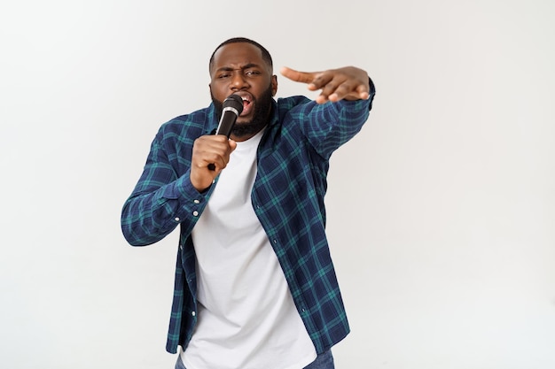 Portret van een jonge man die zingt terwijl hij tegen een witte achtergrond staat