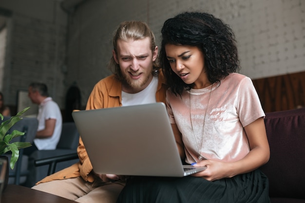 Portret van een jonge man en vrouw die verbaasd naar laptop kijken