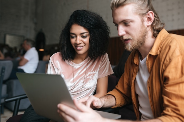 Portret van een jonge man en vrouw zitten in restaurant en die op laptop werkt