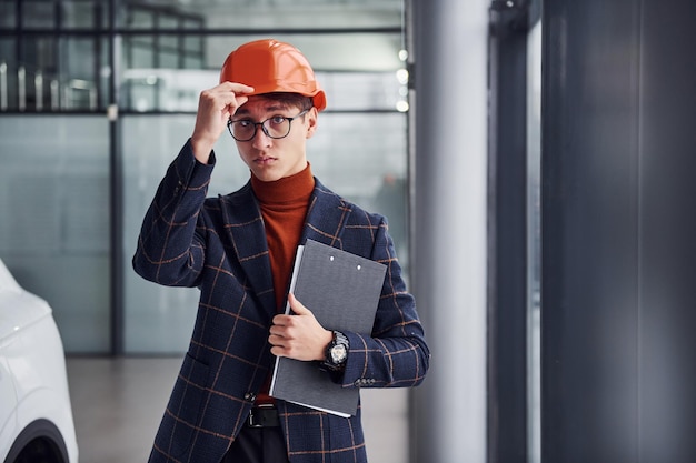 Portret van een jonge man in beschermende helm en in formele kleding die binnenshuis staat.