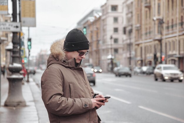 Portret van een jonge man in casual winterkleren met een bril op walk city