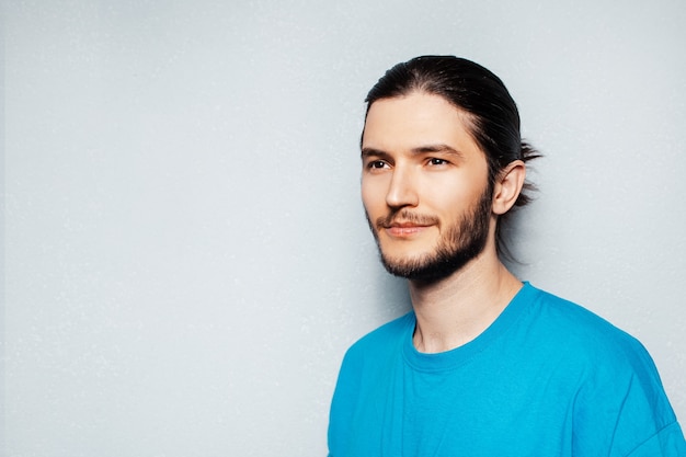 Portret van een jonge man in een blauw shirt op een gestructureerde achtergrond van grijs.