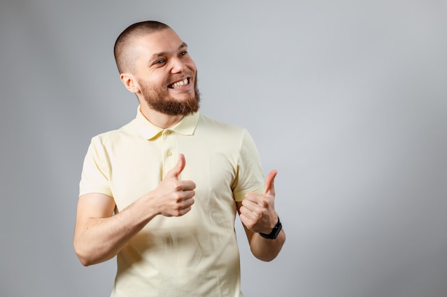 Portret van een jonge man in een geel T-shirt toont zoals op grijs.