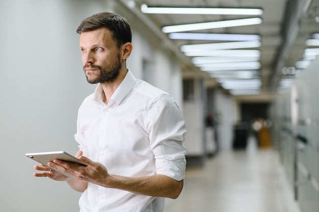 Portret van een jonge man in een wit overhemd op kantoor, de manager op kantoor houdt een laptop van hoge kwaliteit vast