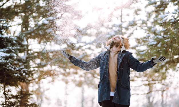 Portret van een jonge man in het besneeuwde winterbos Seizoen kerst reizen en mensen concept