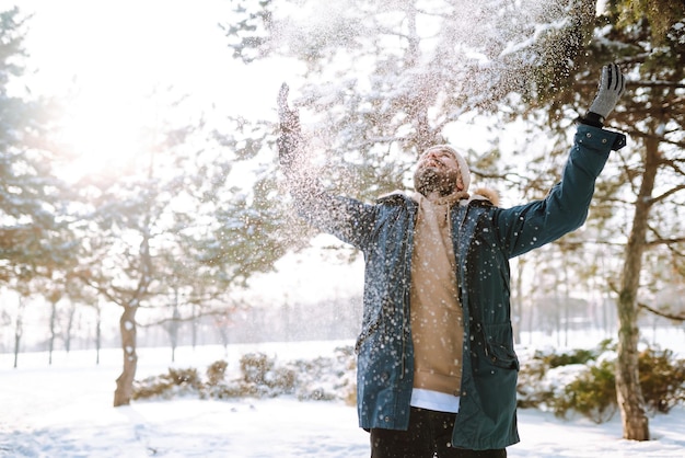Portret van een jonge man in het besneeuwde winterbos Seizoen kerst reizen en mensen concept