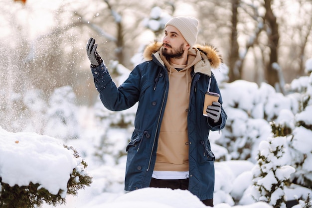 Portret van een jonge man in het besneeuwde winterbos Seizoen kerst reizen en mensen concept