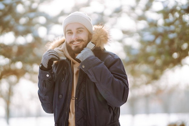 Portret van een jonge man in het besneeuwde winterbos Seizoen kerstreizen en mensenconcept