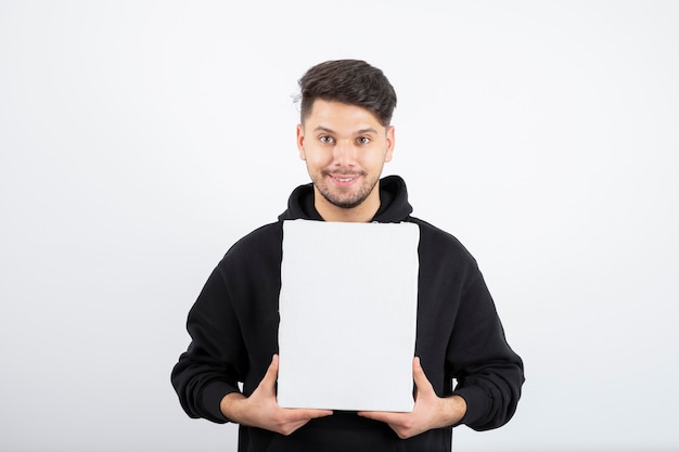 Portret van een jonge man in zwarte hoodie met leeg canvas