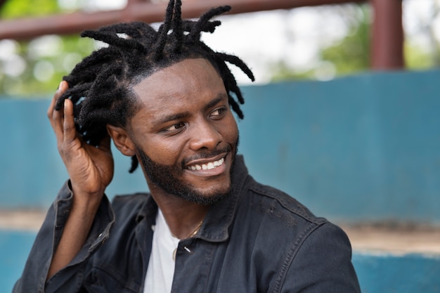 Foto portret van een jonge man met afro-dreadlocks en jas