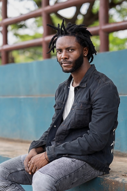 Portret van een jonge man met afro-dreadlocks en jas