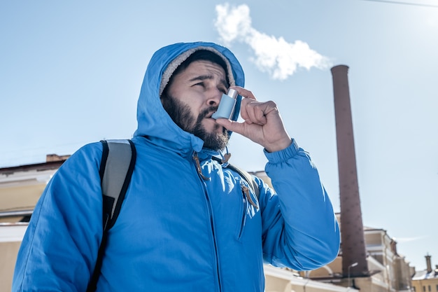 Portret van een jonge man met behulp van astma-inhalator buiten