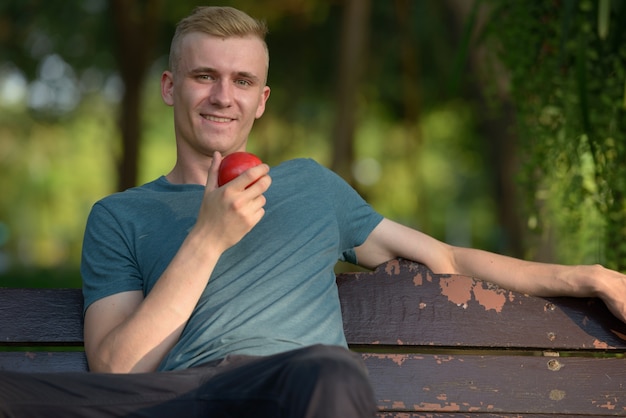 Portret van een jonge man met blond haar in het park buiten