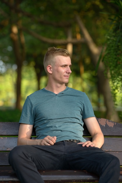 Portret van een jonge man met blond haar in het park buiten