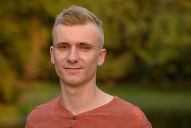 Foto portret van een jonge man met blond haar in het park buiten