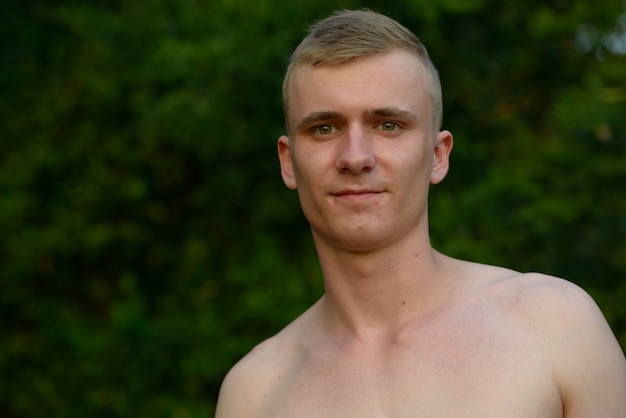 Portret van een jonge man met blond haar shirtless in het park buitenshuis