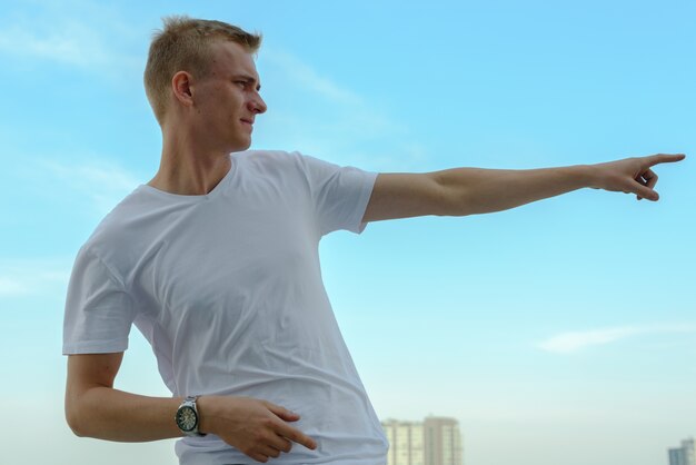 Portret van een jonge man met blond haar tegen de heldere hemel buiten