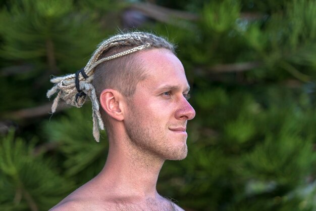 Portret van een jonge man met dreadlocks op zijn hoofd in de natuur Close up