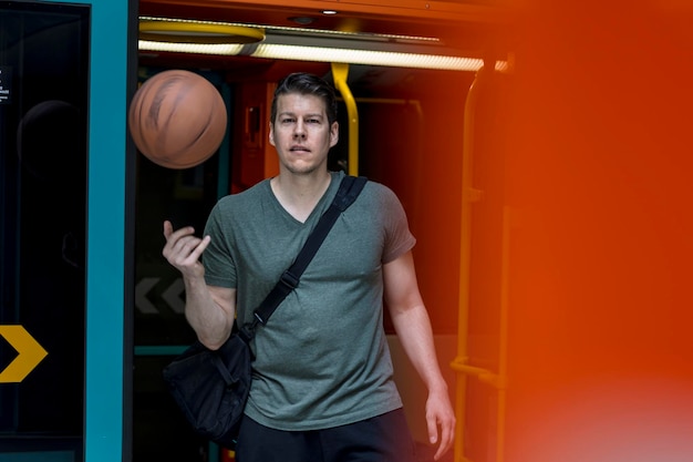 Foto portret van een jonge man met een basketbal bij de ingang van de trein