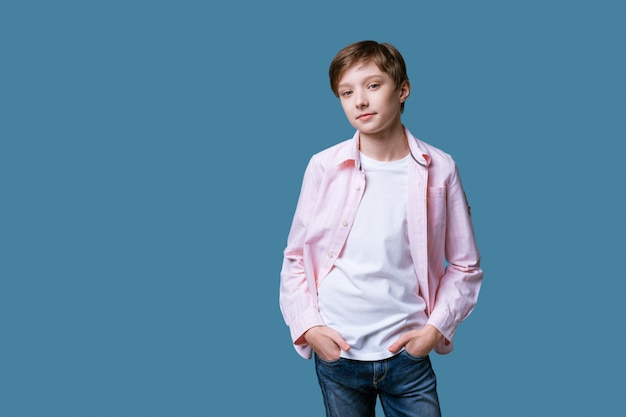 Portret van een jonge man met een europees uiterlijk in een wit t-shirt en een roze shirt poserend op een blauwe muur