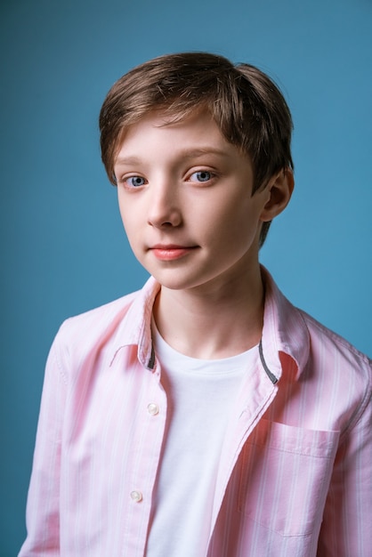 Portret van een jonge man met een europees uiterlijk in een wit t-shirt en een roze shirt poserend op een blauwe muur