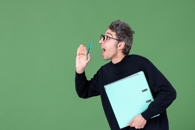 Portret van een jonge man met een groen document op een groene achtergrond zakelijk werk leraar les