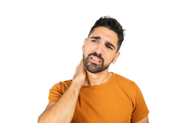 Portret van een jonge man met hand op nek met nekpijn. Geïsoleerde witte muur. Gezondheid concept.