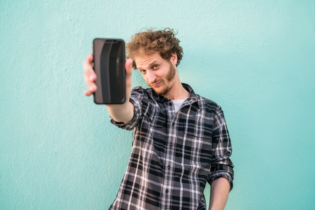 Portret van een jonge man met lege gescreende smartphone.