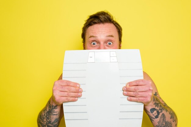 Foto portret van een jonge man met papier op een gele achtergrond