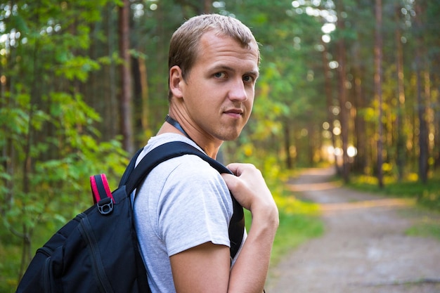 Portret van een jonge man met rugzak wandelen in het bos