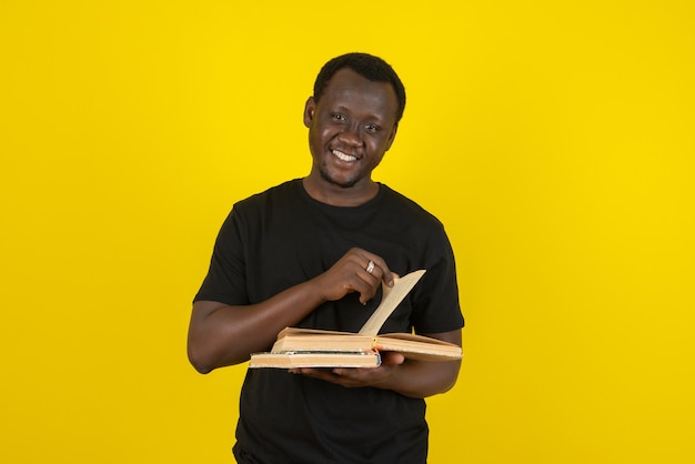 Portret van een jonge man model met boeken tegen gele muur