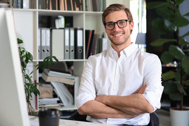 Portret van een jonge man zit aan zijn bureau in het kantoor