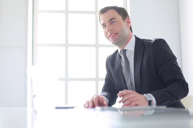 Portret van een jonge man zit aan zijn bureau in het kantoor