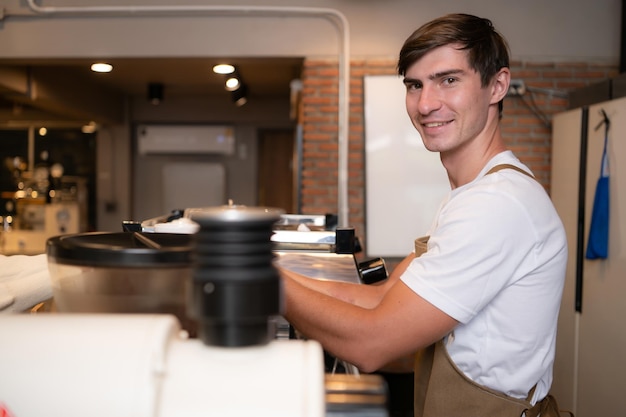 Foto portret van een jonge mannelijke barista die koffie bereidt in een koffieshop