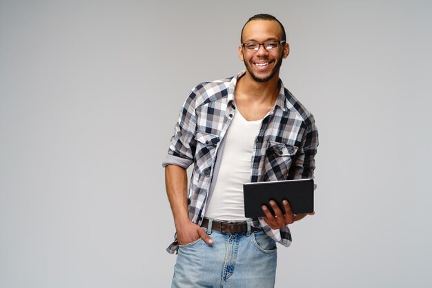 Portret van een jonge mens die het groene stootkussen van de tabletpc van de t-shirtholding draagt