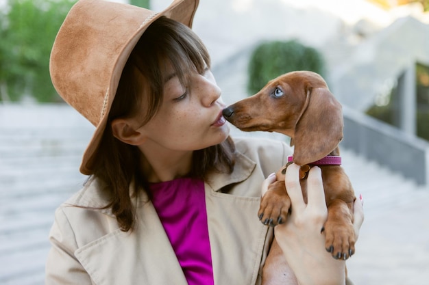 Portret van een jonge modevrouw en een mooie teckelpuppy in een stadspark. Meesteres en huisdier