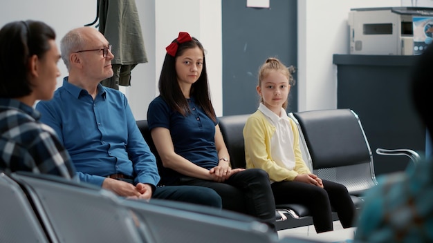 Portret van een jonge moeder en een klein meisje dat in de wachtkamer zit en een afspraak heeft met de arts in de medische kliniek. vrouw met kind in de ontvangsthal van het ziekenhuis, wachtend in de rij.