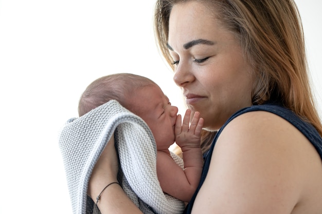 Portret van een jonge moeder met een pasgeboren baby in haar armen.