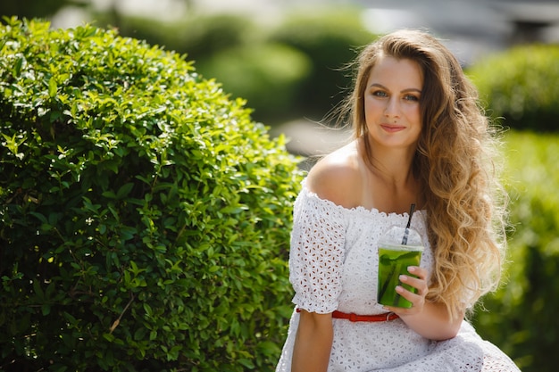 Portret van een jonge mooie aantrekkelijke vrouw buiten in de zomer met een glas ijskoud sap of drankje. Mooi meisje buiten met verse mojito