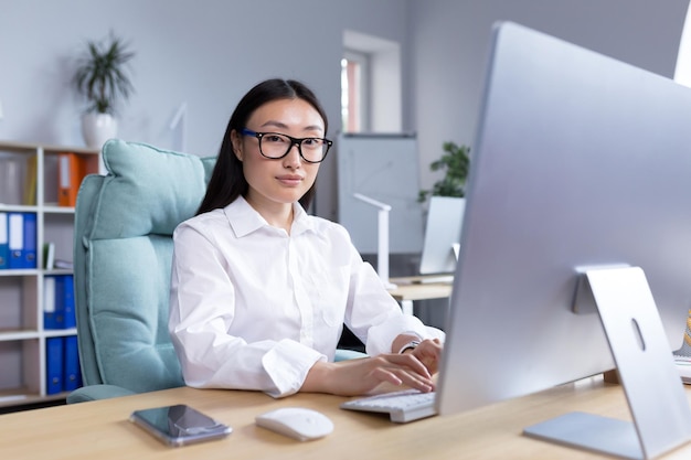 Portret van een jonge, mooie aziatische vrouw op kantoor, zakenvrouw directeur freelancer in een wit