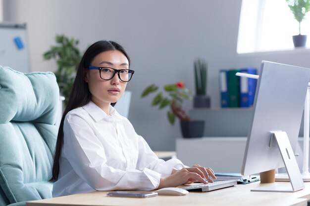 Portret van een jonge, mooie aziatische vrouw op kantoor, zakenvrouw directeur freelancer in een wit