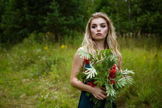 Portret van een jonge mooie blonde vrouw met een boeket van lijsterbessen in de natuur close-up