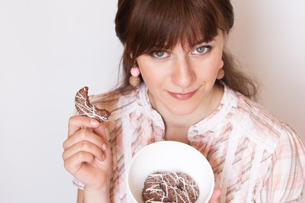 Portret van een jonge, mooie brunette die geniet van heerlijke chocoladekoekjes