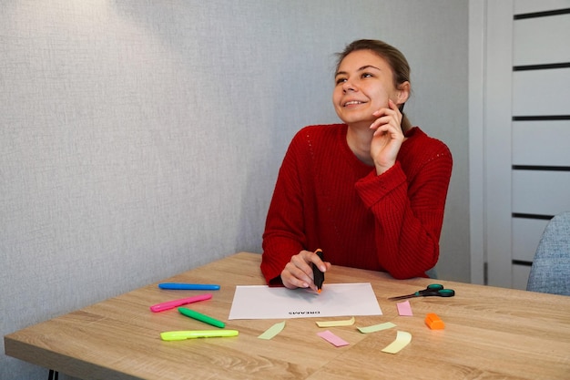 Portret van een jonge, mooie nadenkende dame die haar dromenlijst opschrijft Visualisatie van dromen