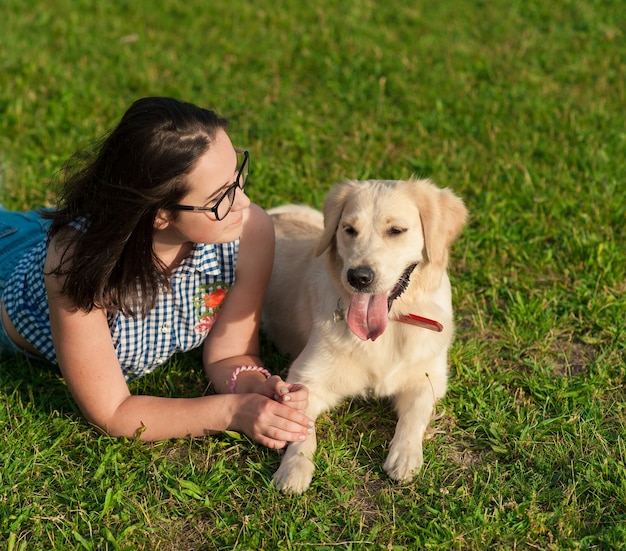 Portret van een jonge mooie vrouw die haar golden retriever-hond zit en knuffelt.